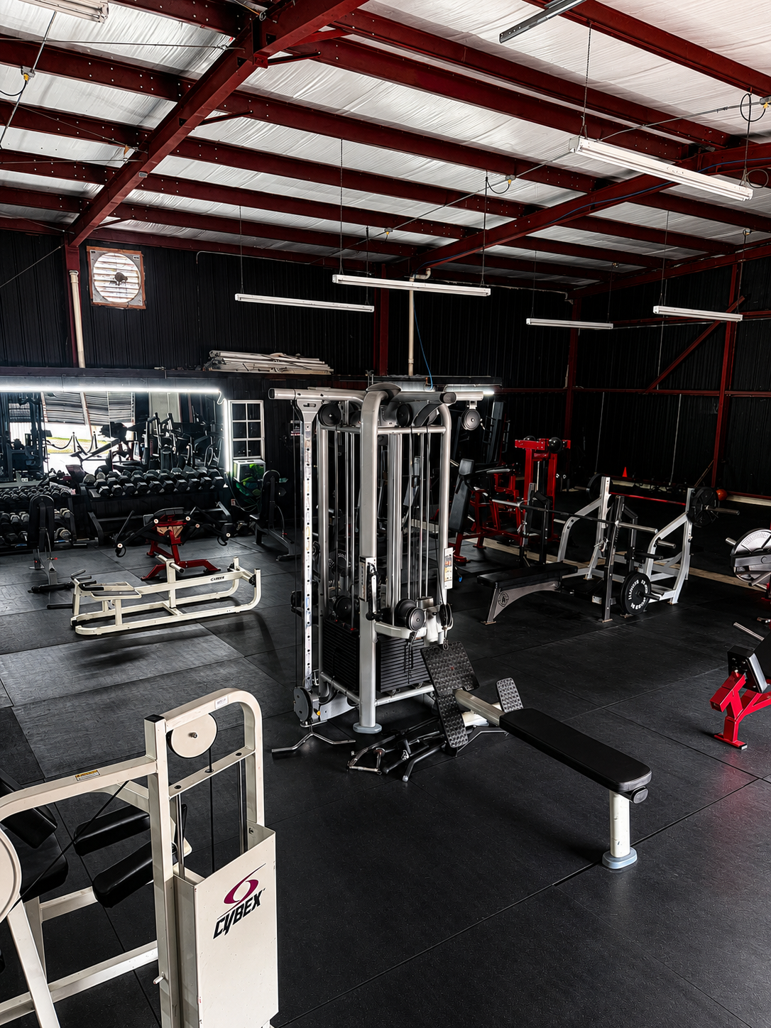 Cable machine, dumbbells, and bench across the warehouse floor